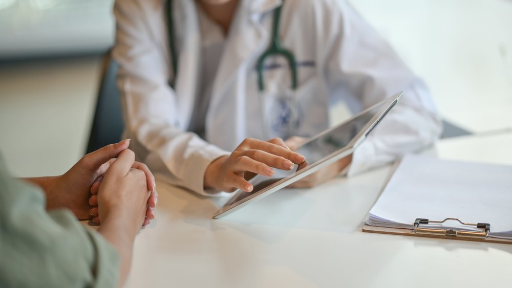 Photo d'illustration : Une médecin montre des information à une patiente sur une tablette connectée. Personnel de santé. Parcours de santé. Parcours de soin. Valorisation de la données. Numérique.